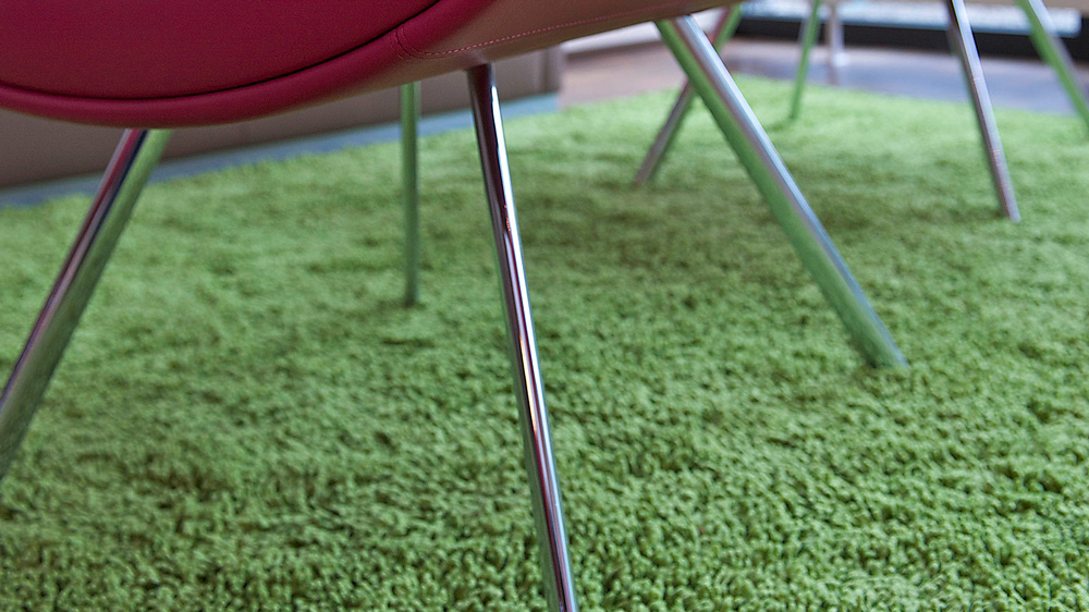 Grüner Teppichboden und roter Lounge-Sessel